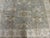 Soft grey field decorated with soft flowing motifs within ivory border.