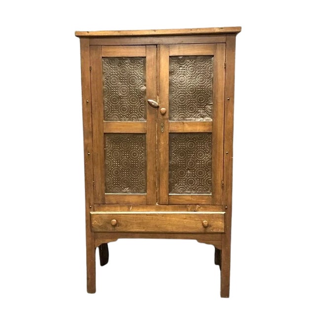 A late 19th-century American primitive pie safe, circa 1885, featuring four richly patterned punched-copper-finished tin...