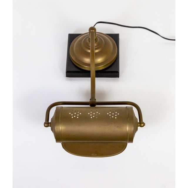 An early 20th century, well crafted and designed piano lamp with a pivoting shade pierced with three "snowflakes" on the...