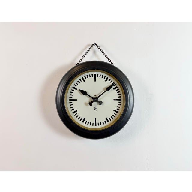 This wall clock was produced by Siemens in Germany during the 1930s. It features a black metal frame, a metal dial and a...