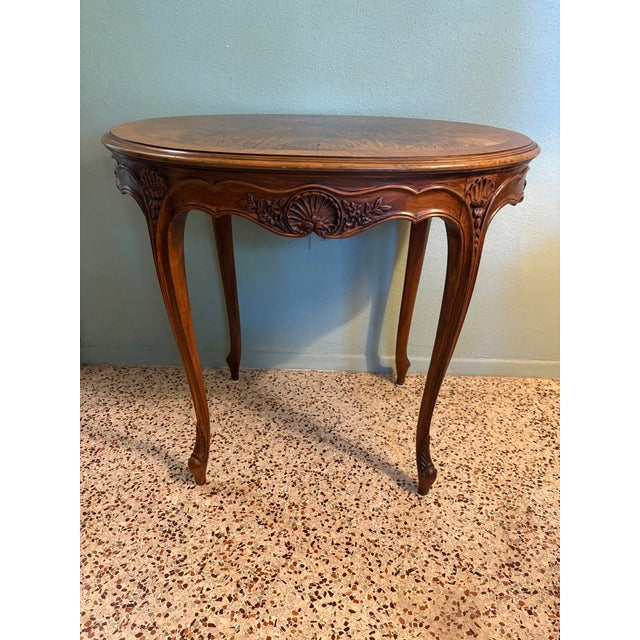A beautifully crafted oval side table in the Louis XV style, featuring graceful cabriole legs, a scalloped and carved...