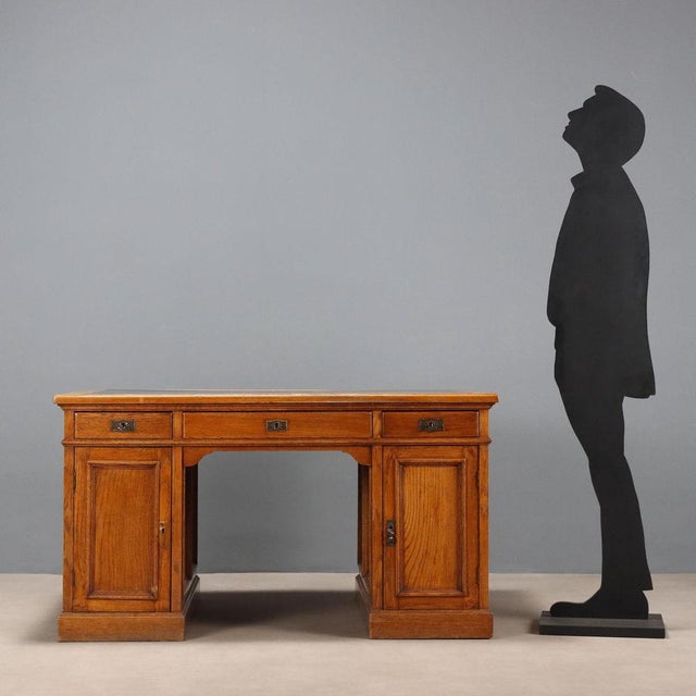 Oak desk. Top with black leather insert, three drawers in the lower section and doors in the side panels. Handles and...