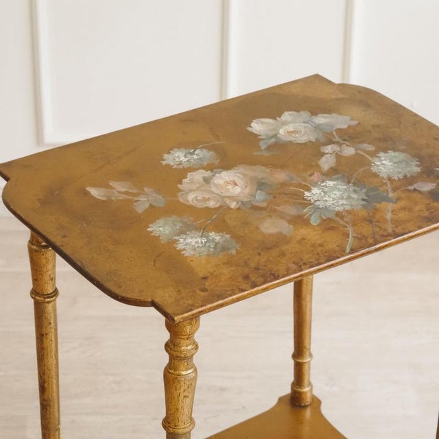 A two-tiered side table from the belle époque period, circa 1880–1900, with hand-painted floral decoration on a lacquered...