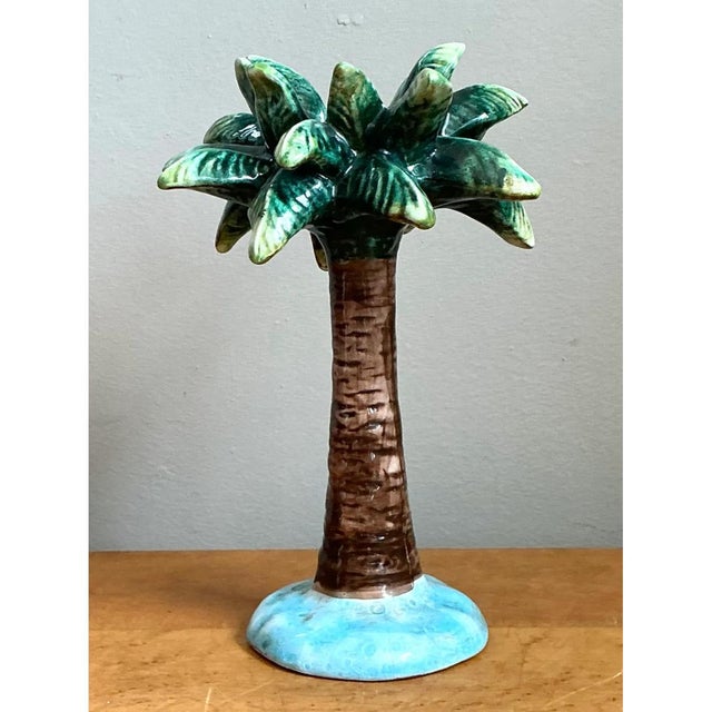 This candlestick takes the whimsical form of a full-scale palm tree, its slender trunk rising from a rounded island-blue...