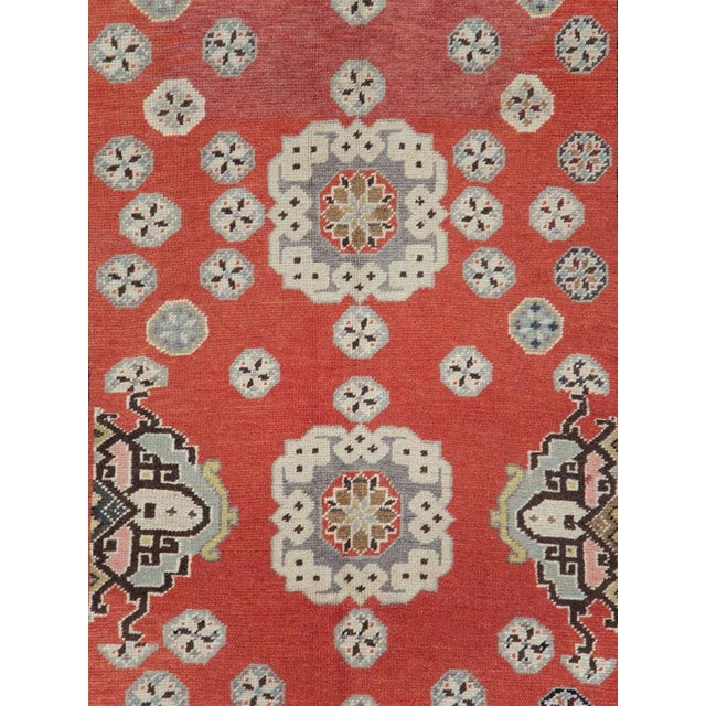 This mid-20th-century Turkish Anatolian gallery rug presents a richly ordered composition across a warm brick-red field....