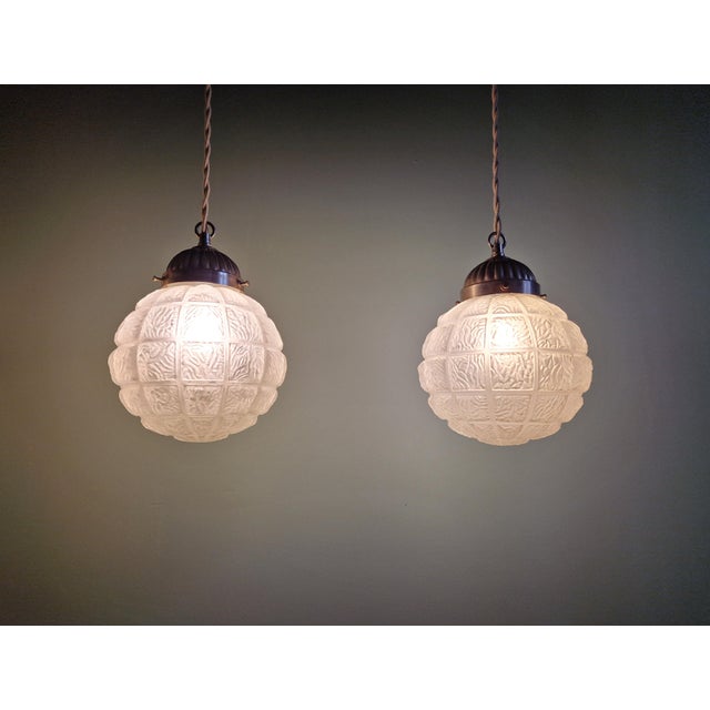 Pair of Art Deco pendant lights in molded, pressed frosted glass with chromed metal brackets, 1920s-30s. Each light has...