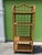 Charming vintage rattan étagère featuring a tall, airy silhouette, gracefully arched top, and four woven cane shelves....