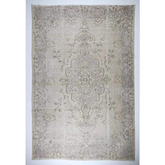 This soft Turkish hand-knotted wool on cotton rug features a beautifully faded palette of ivory, stone gray, and subtle...