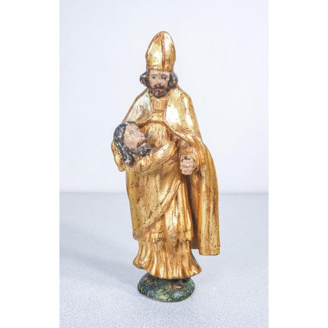 Group of three gilded wooden sculptures: saint francis of assisi, saint gratus of aosta with the head of john the baptist,...