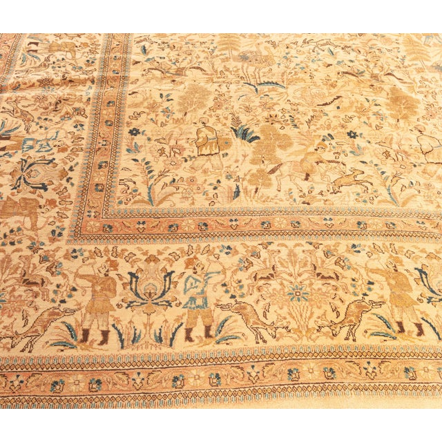 An early 20th century Persian Tabriz rug, the cream field with a naturalistically-drawn hunting scene with scattered...