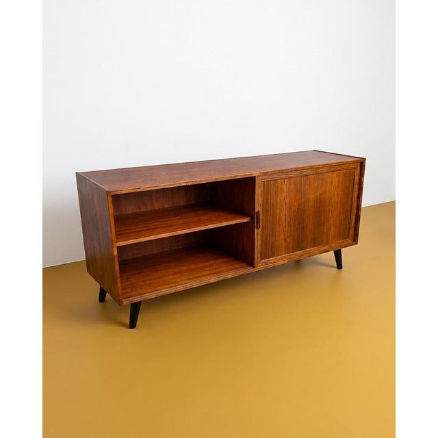 A compact 160 cm Danish teak sideboard from the 1960s with sliding doors and drawers. The diagonally tapered legs maintain...
