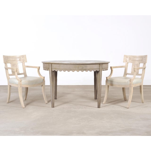An iconic and refined set of five labeled "White Klismos" dining chairs by Michael Taylor Designs comprising of two host...