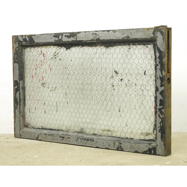 Reclaimed rectangular shaped window with a wood frame, steel sides, and a clear wormy chicken wire glass pane. It was...