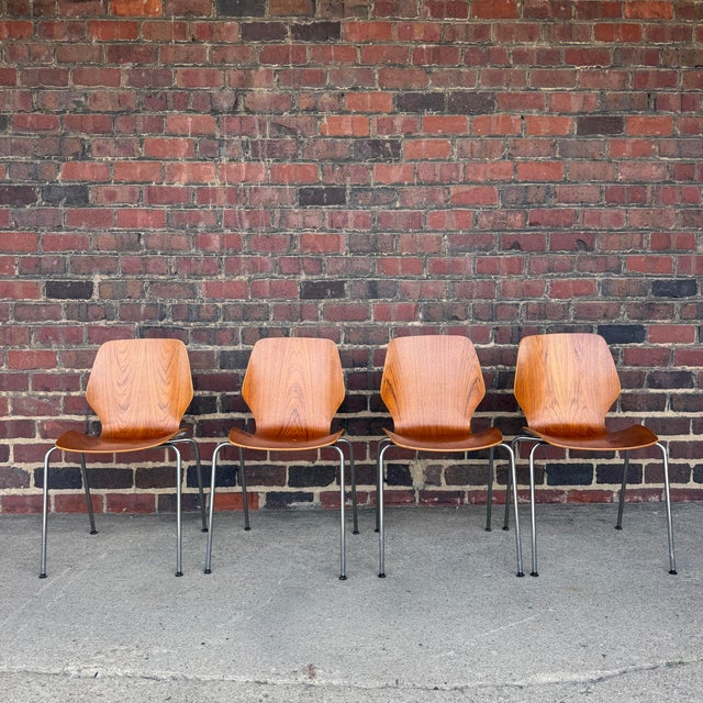 Set of four mid-century modern dining chairs by Westnofa. The chairs feature molded teak seats and backs with chrome metal...