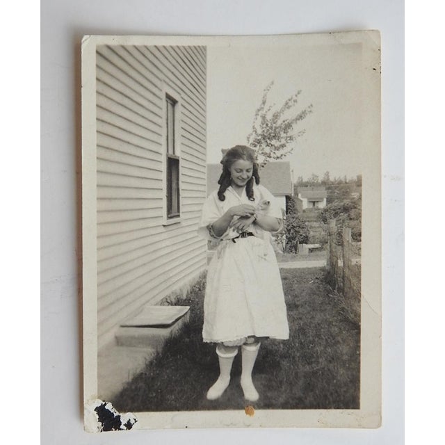 Early 20th century snapshot photograph of a young woman and her kitten. Unframed, black album corner remnants.