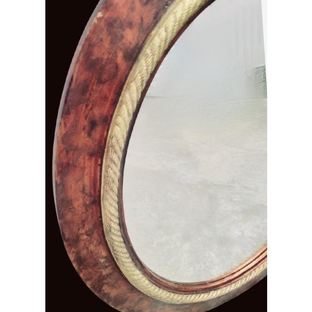 A pair of custom painted tortoiseshell oval wall mirrors. The mirrors feature a faux tortoiseshell finish in a mix of...