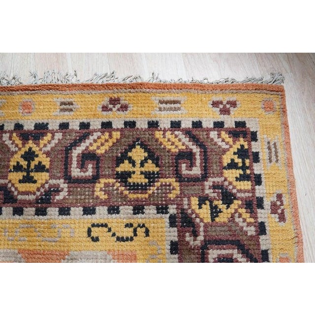 This hand knotted wool rug features a primary color palette of yellow, gold, and orange. Crafted in India, the rug...