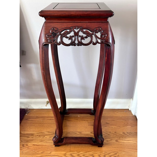 A beautifully carved Chinese rosewood pedestal plant stand, featuring elegant curved legs and intricate openwork carving...