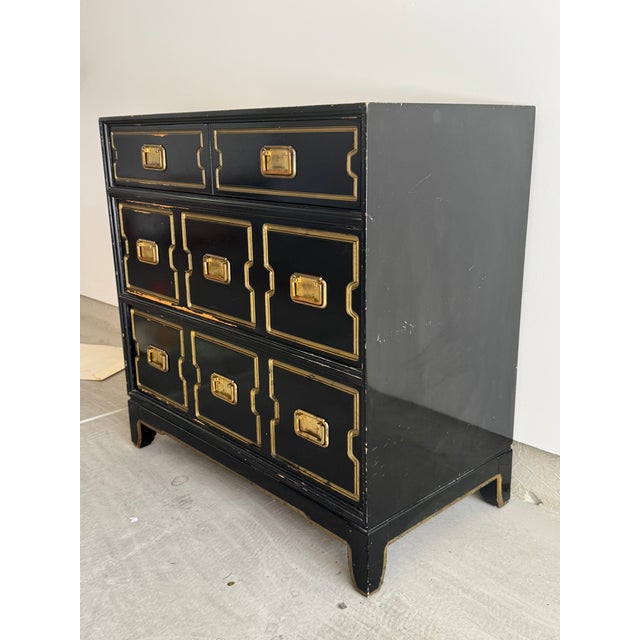 This. beautiful chest of drawers features three drawers with brass Campaign style hardware and incised design in gold....