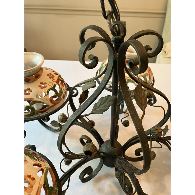 Black wrought-iron chandelier with five arms adorned with additional iron flourishes as well as tole gilt leaves and buds....