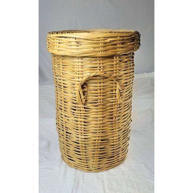 Handcrafted wicker laundry hamper with a matching lid and dual side handles for easy transport. This tall cylindrical...