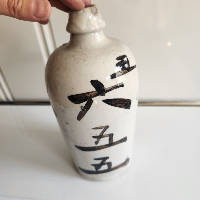 A heavy stoneware saki bottle. Inscribed with the name of the owner. Very rustic with pops n bubbles to the glaze