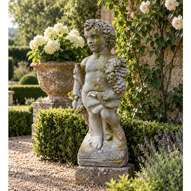 A wonderfully weathered late 20th-century cast concrete garden figure depicting a classical putto carrying abundant...