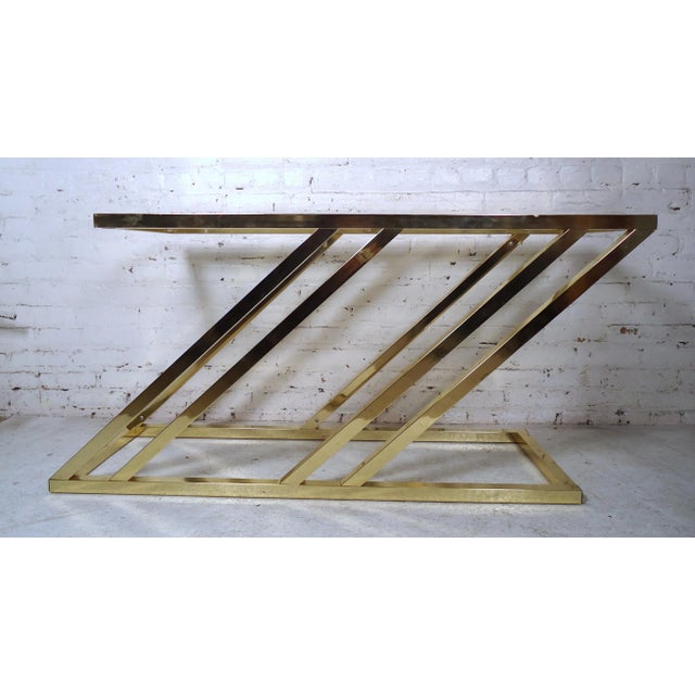Uniquely designed brass console featuring a glass top, this console would make a great addition to any home or office.