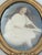 An antique photograph portrait of a young girl in an ornate, possibly French, oval gesso frame with convex bubble glass....