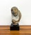 An expressive vintage hand-carved stone sculpture depicting an abstract human bust with stylized facial features and an...
