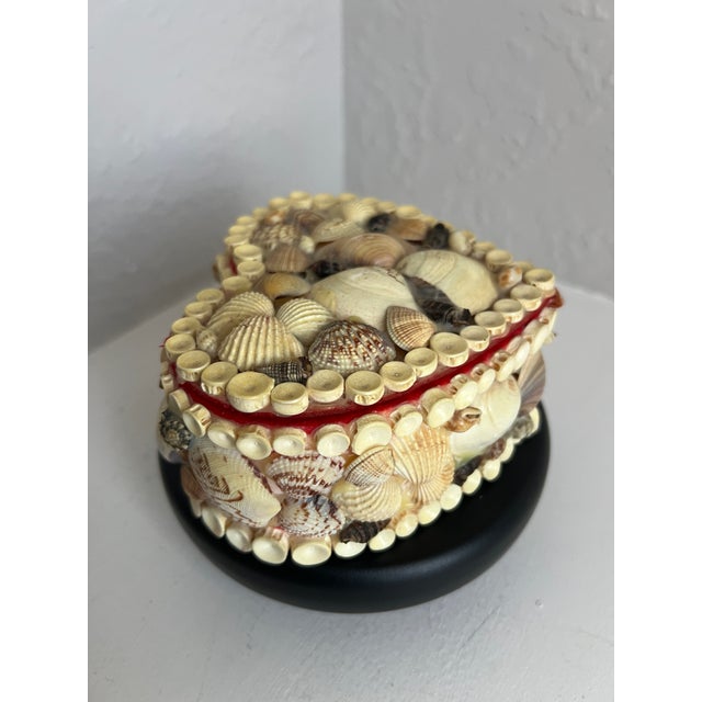 A beautifully handcrafted vintage heart-shaped trinket box adorned with real seashells and lined in rich red velvet. The...