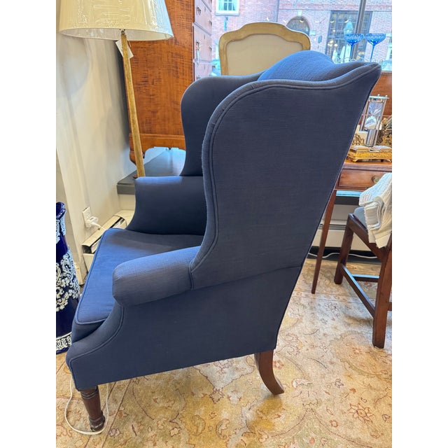 This is an 1800s antique wingback chair. It is newly reupholstered with a beautiful blue linen. The armrests feature a...