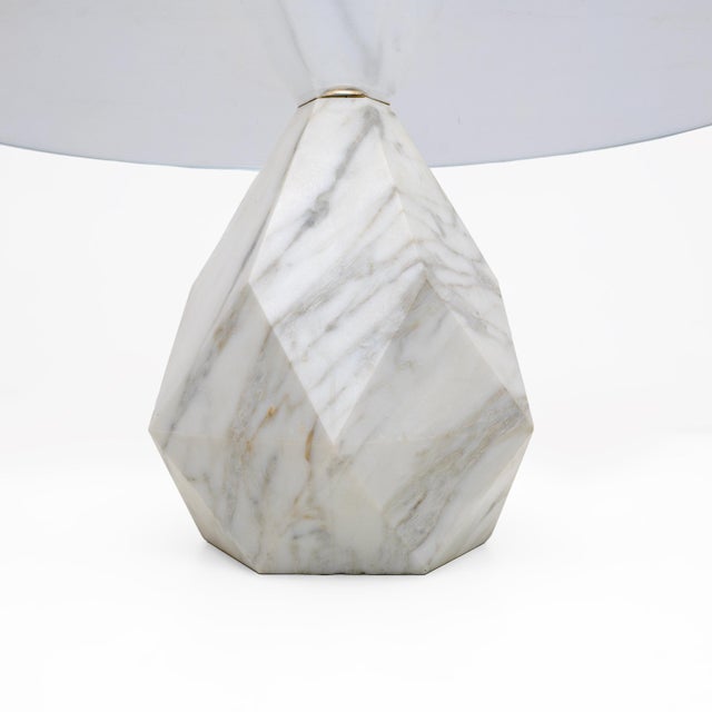 Modern minimalist coffee table with a thick circular top made of clear glass. The central base of the table is made of...