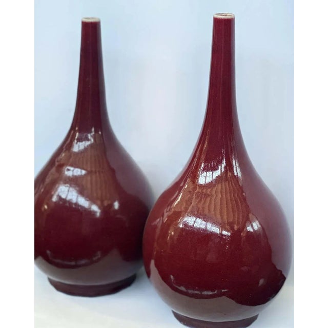 Pair of traditional 20th century Sang de Boeuf vases. Crafted from fine earthenware, each vase boasts a striking deep red...