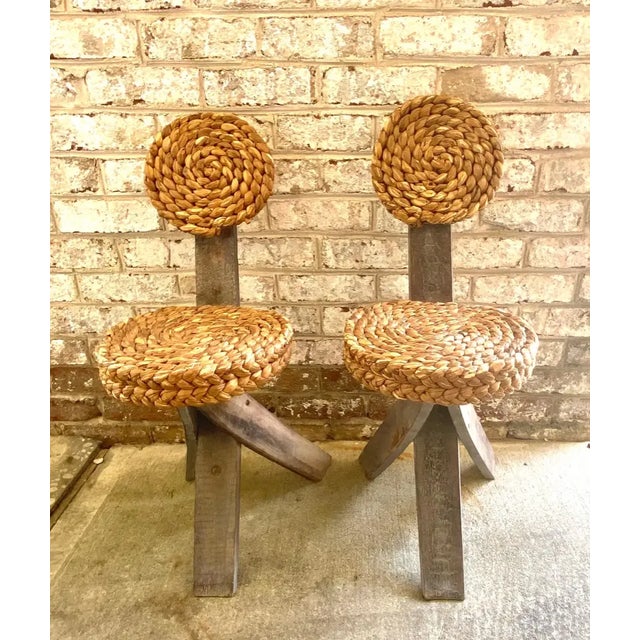 A unique pair of Audoux Minet tripod base chairs with abaca seats and backs.