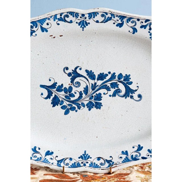 This 18th-century French faience dish from Strasbourg is decorated in blue and white with a lush spray of scrolls and...