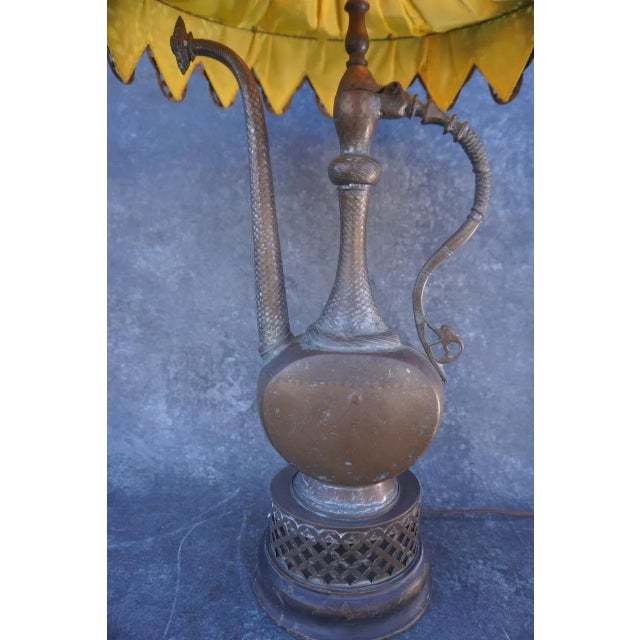 Unique brass table lamp featuring a distinctive Indo-Asian samovar-inspired design. The pierced metal lampshade is lined...