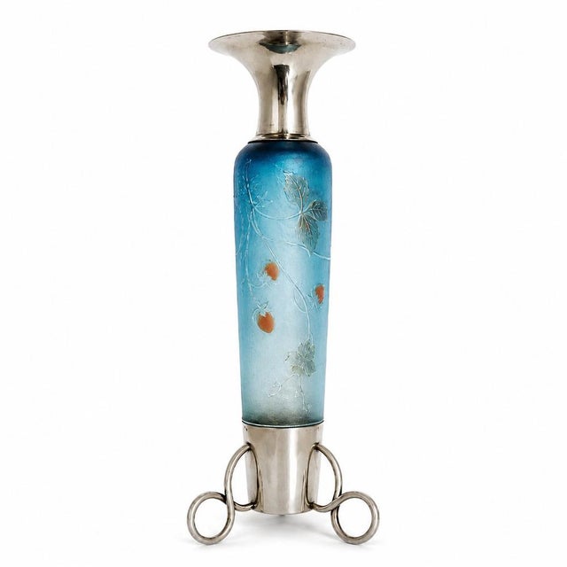 A refined Art Nouveau pitcher from Daum Nancy, combining frosted blue glass with Portuguese silver details. The body is...