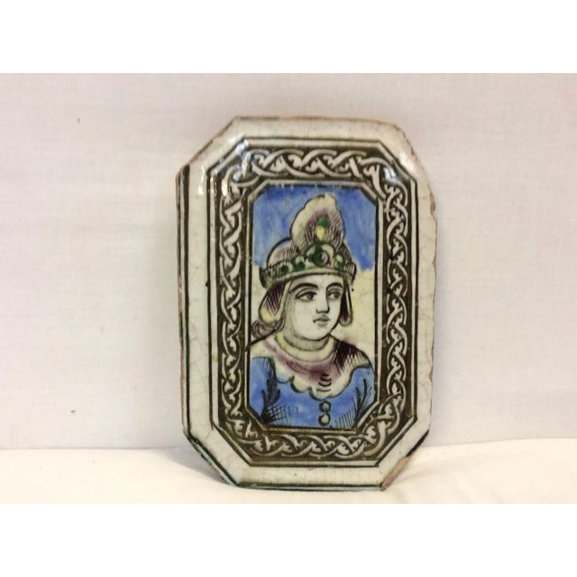 This is a salvaged tin glazed middle eastern tile depicting a painted figure in a braided frame.