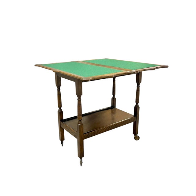 A handsome early 20th-century English Jacobean-style oak trolley featuring a beautifully carved apron, elegant turned...