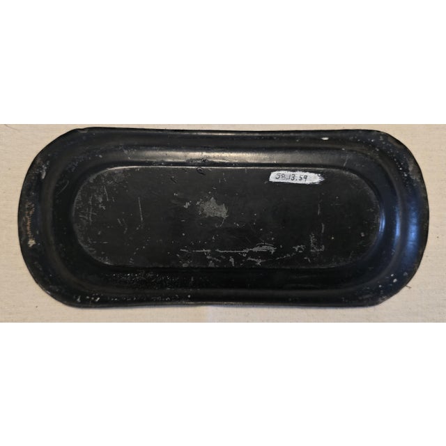An elongated rectangular painted tin tray with rounded ends, finished in a black ground and decorated in the chinoiserie...