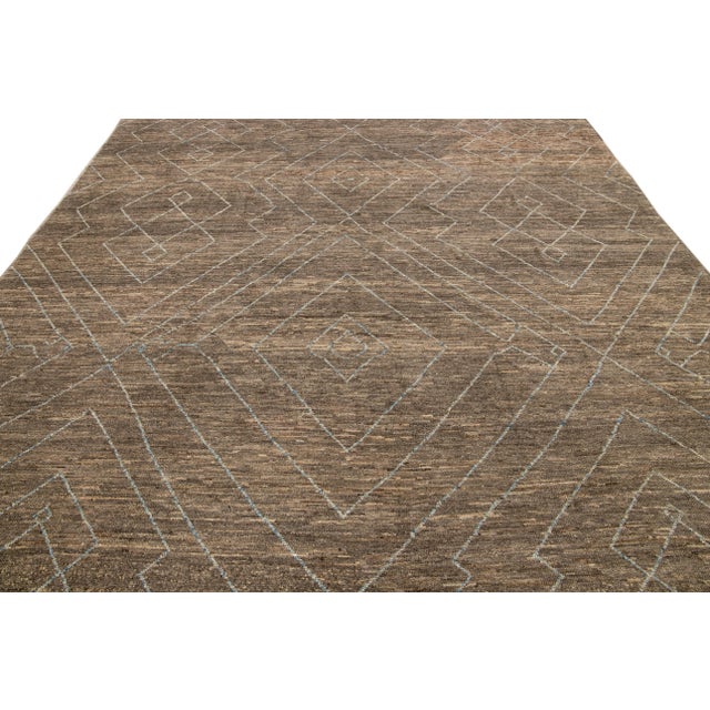 Beautiful Moroccan style handmade wool rug with a brown field. This Modern rug has beige and blue accents featuring a...