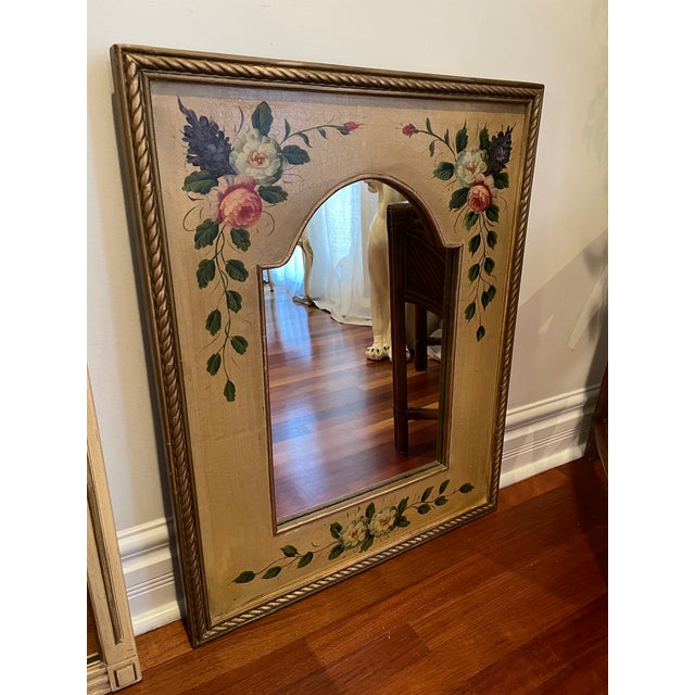 A decorative French Country Revival mirror featuring hand-painted floral garlands set against a softly crackled ground....