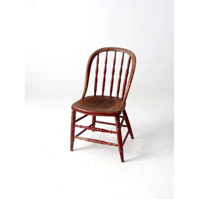 An antique Windsor chair with a classic bow-back silhouette, turned spindles, and gracefully turned stretchers. The chair...