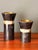 Pair of tessellated horn and mother of pearl candleholders with brass inserts in the manner of Maitland Smith. Larger is...
