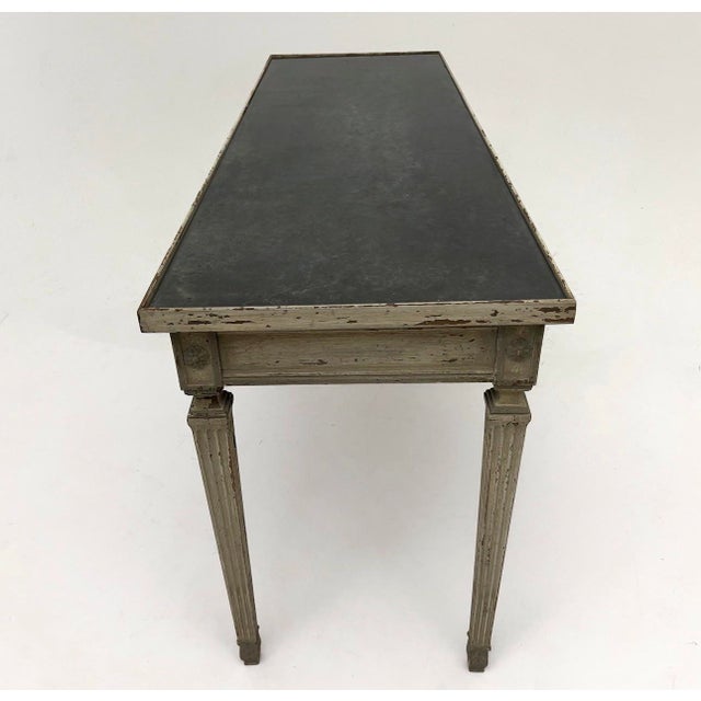 An exceptionally stylish neoclassical-style console table featuring a beautifully distressed painted finish, elegant...