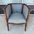 This elegant barrel-back chair features a warm wood frame accented with delicate inlay, gently curved sides, and slender...