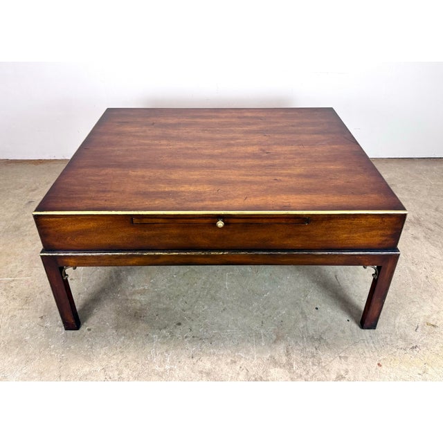 A large and impressive campaign style mahogany and brass coffee table by Theodore Alexander circa late 20th century....