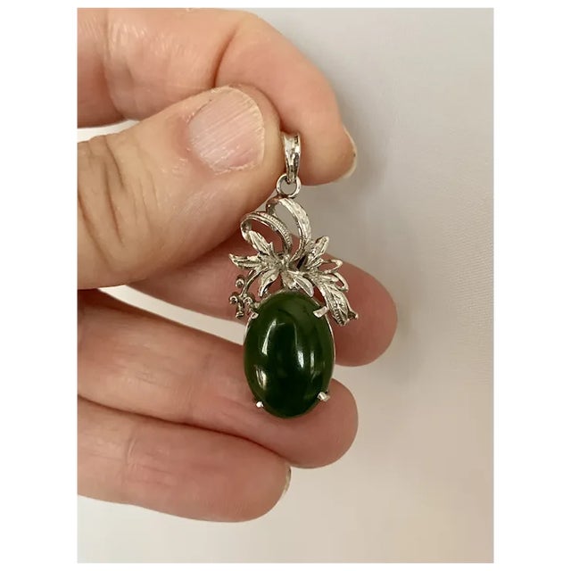 Unique, 1950s 18k white gold pendant. The pendant measures 1 1/2" from top to bottom and features an oval shaped jade...