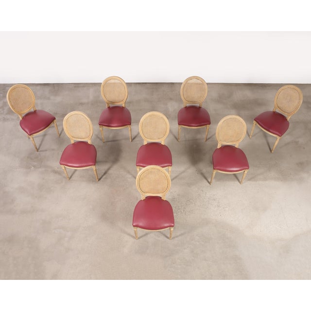 A refined and graceful set of eight French painted dining chairs featuring oval cameo cane backs made in the grand Louis...